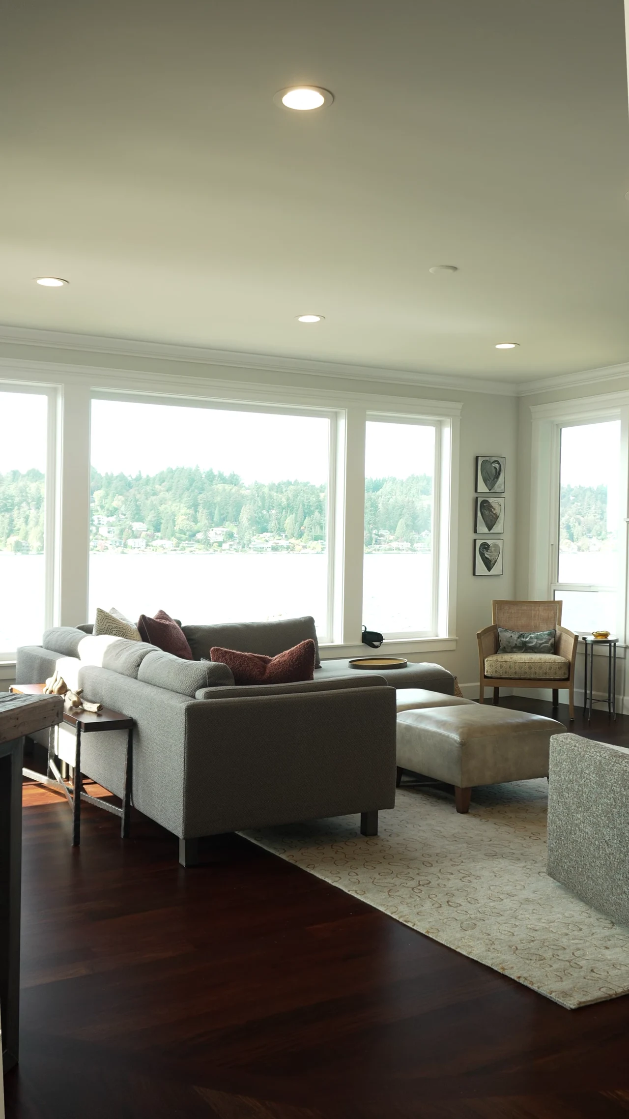 A completed living room with timber floors and large windows overlooking the water.