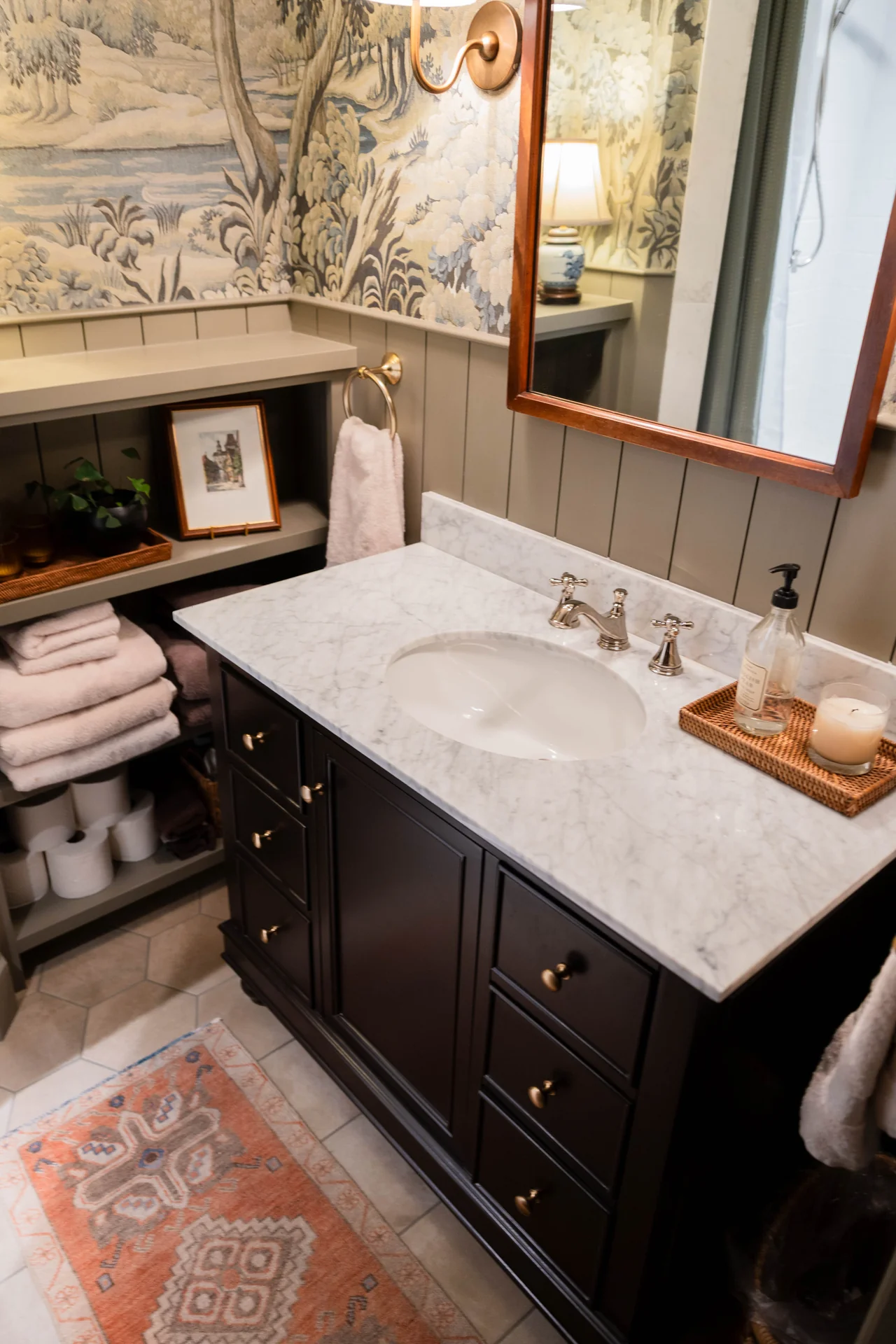 A marble-topped vanity framed by patterned wallpaper and warm painted paneling.