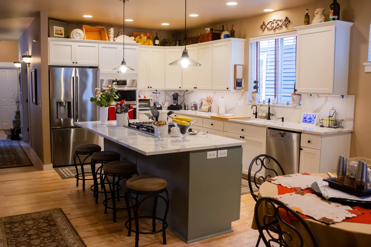 A wide view of the remodeled kitchen, with island seating and white cabinetry.