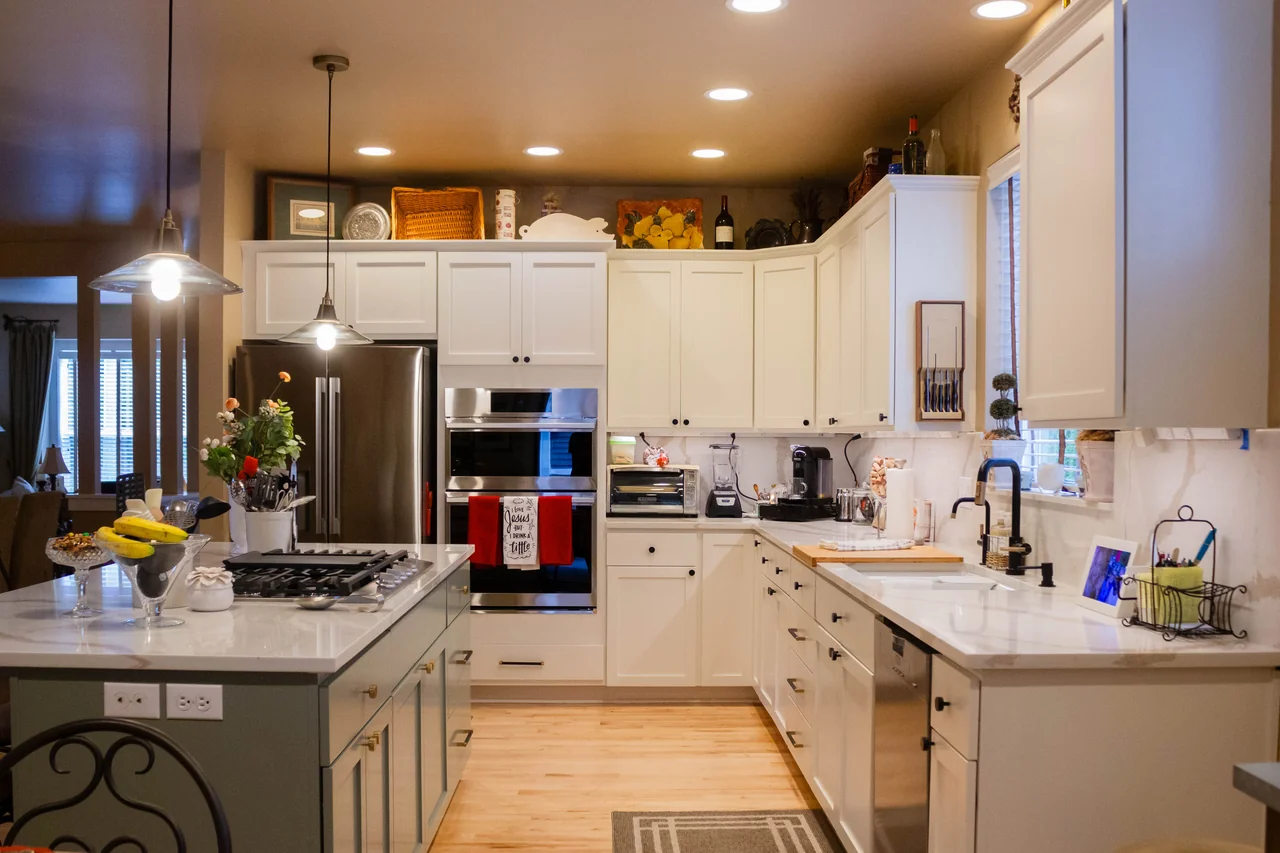 A kitchen with bright cabinetry, a spacious island, and natural wood floors.